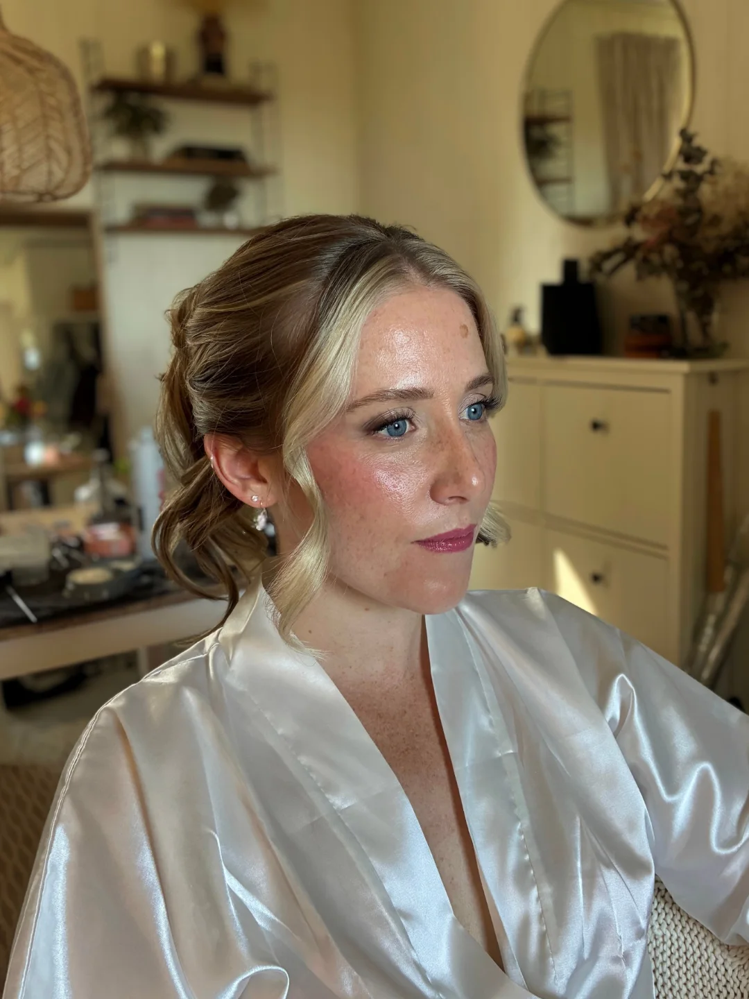 Bride in a satin robe with a soft updo and glowing skin