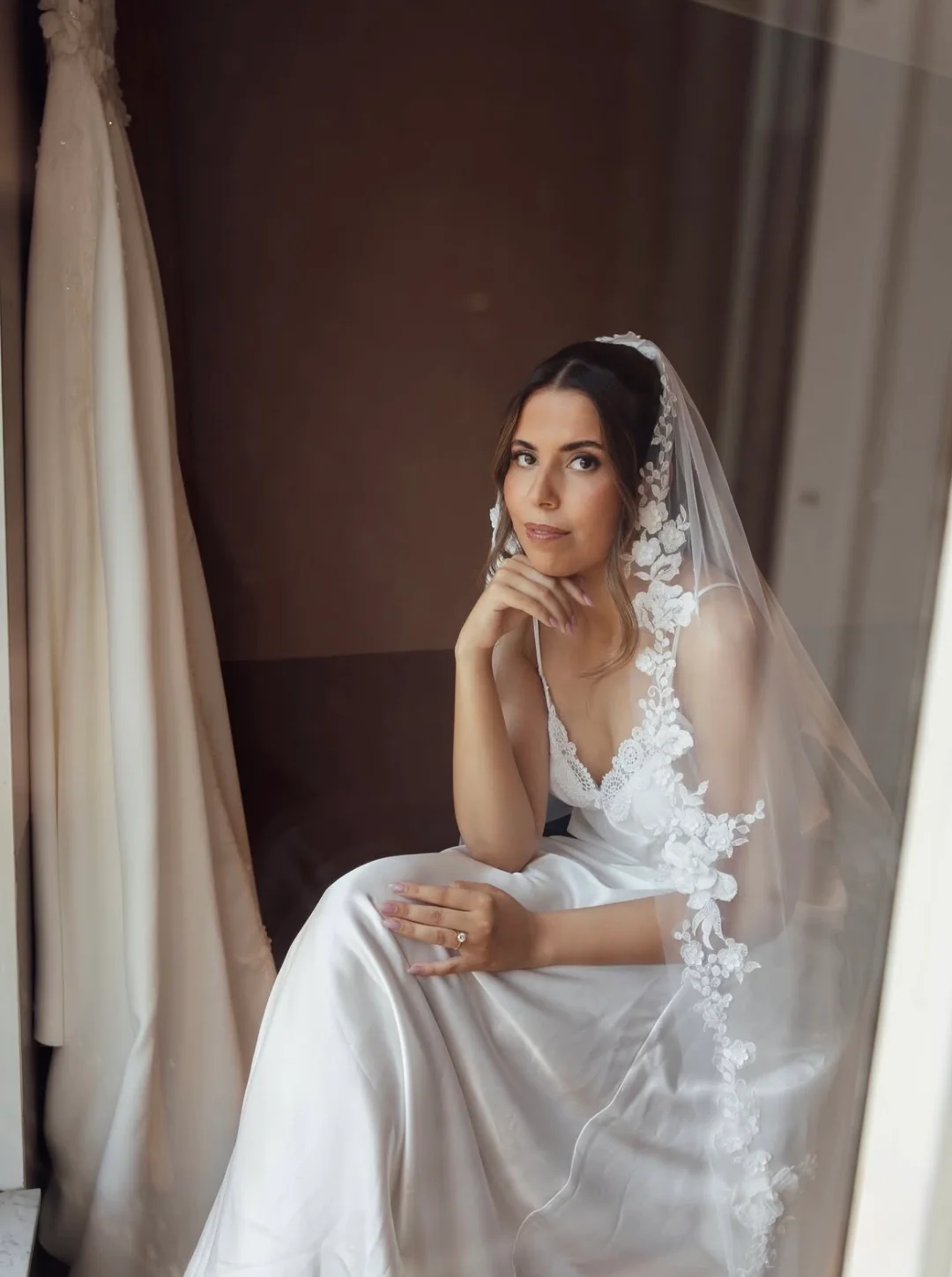 A bride in a lace veil sitting by the window