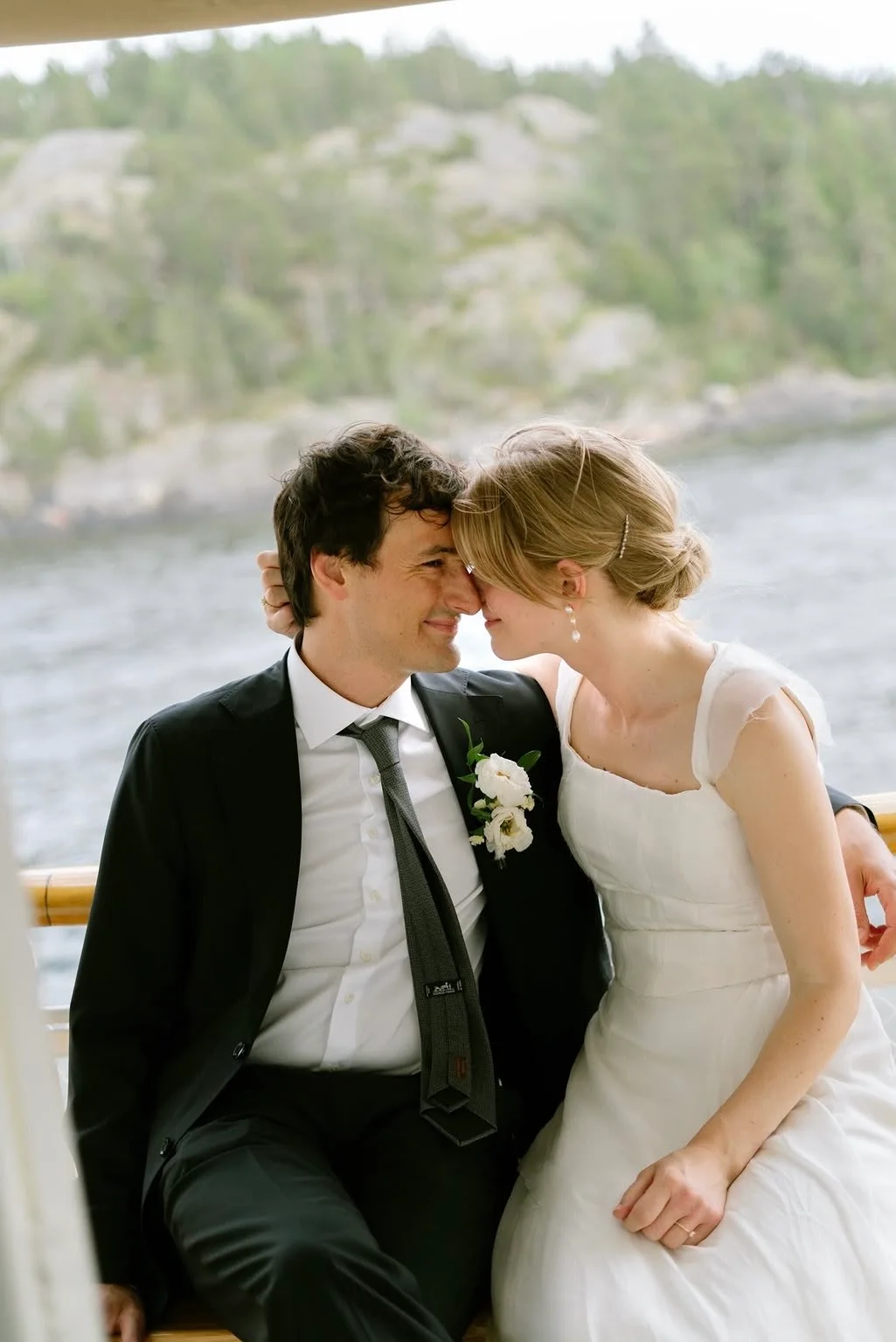 A bride and groom resting their foreheads together on a boat in the archipelago