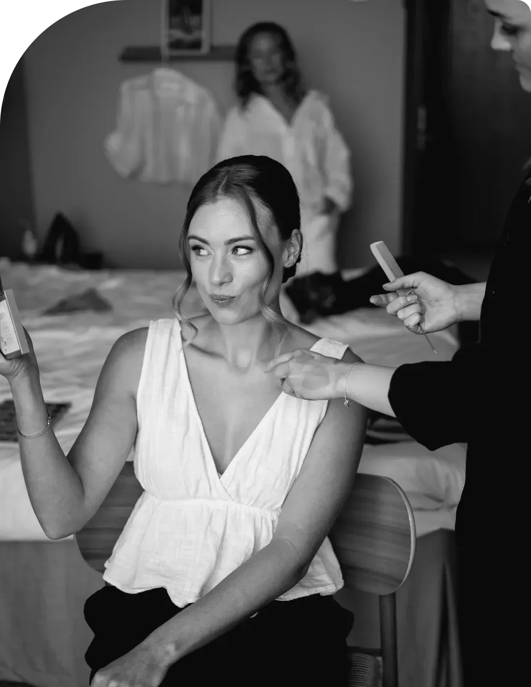 A bride getting her makeup done on her wedding morning, black and white